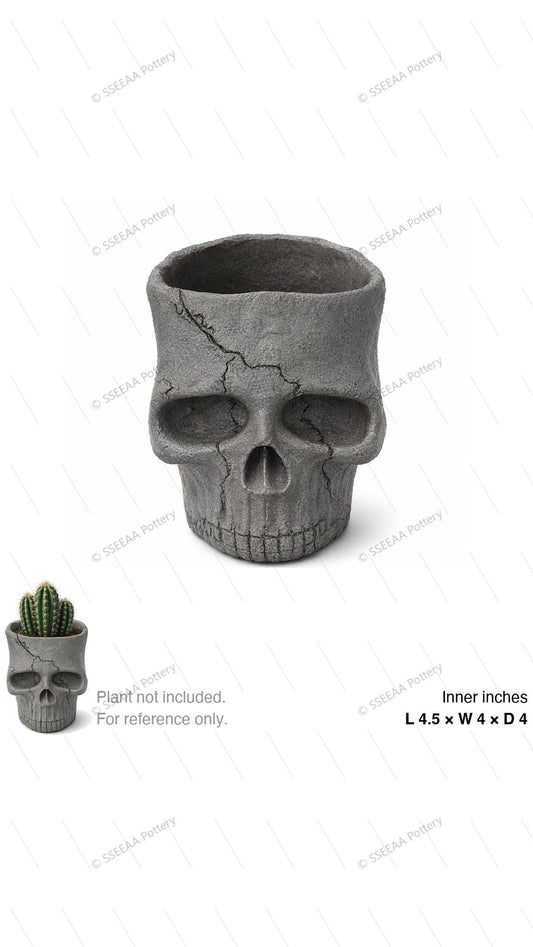 Gray skull-shaped ceramic pot with cracked weathered texture and open top.