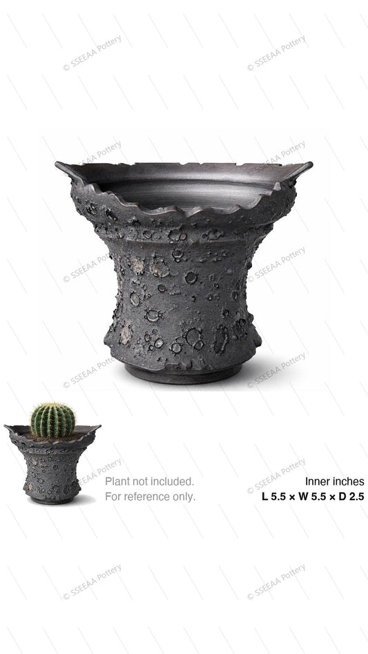 Charcoal craggy footed pot with flared scalloped rim and cratered texture