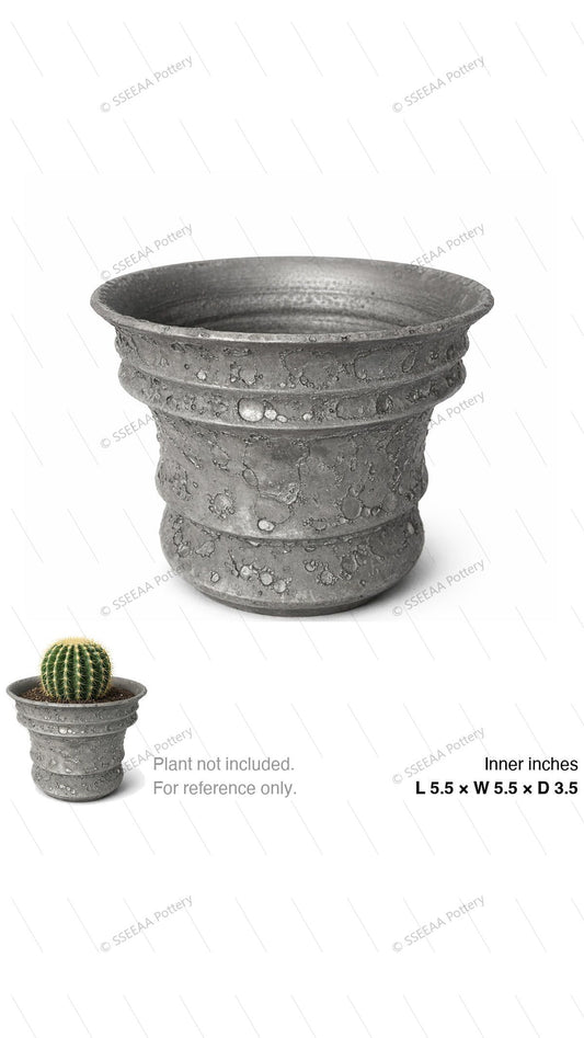 Textured grey footed pot with pitted finish and wide rim shown on white background.