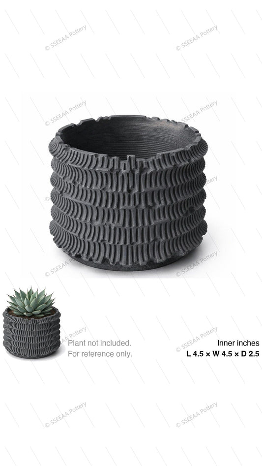 Dark ribbed ceramic pot with a sculptural rounded profile and textured fluted sides on a white background.